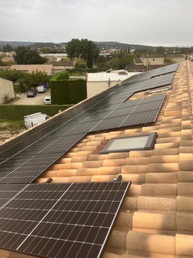 Panneaux solaires installés sur un toit en tuiles. Paysage rural en arrière-plan.